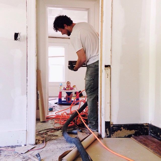 Nathan working on a historic home remodel with his baby in a bouncer in the next room