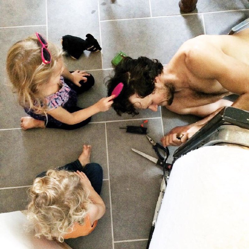 Nathan's daughters brushing his hair while he works on the floor during a live-in remodel