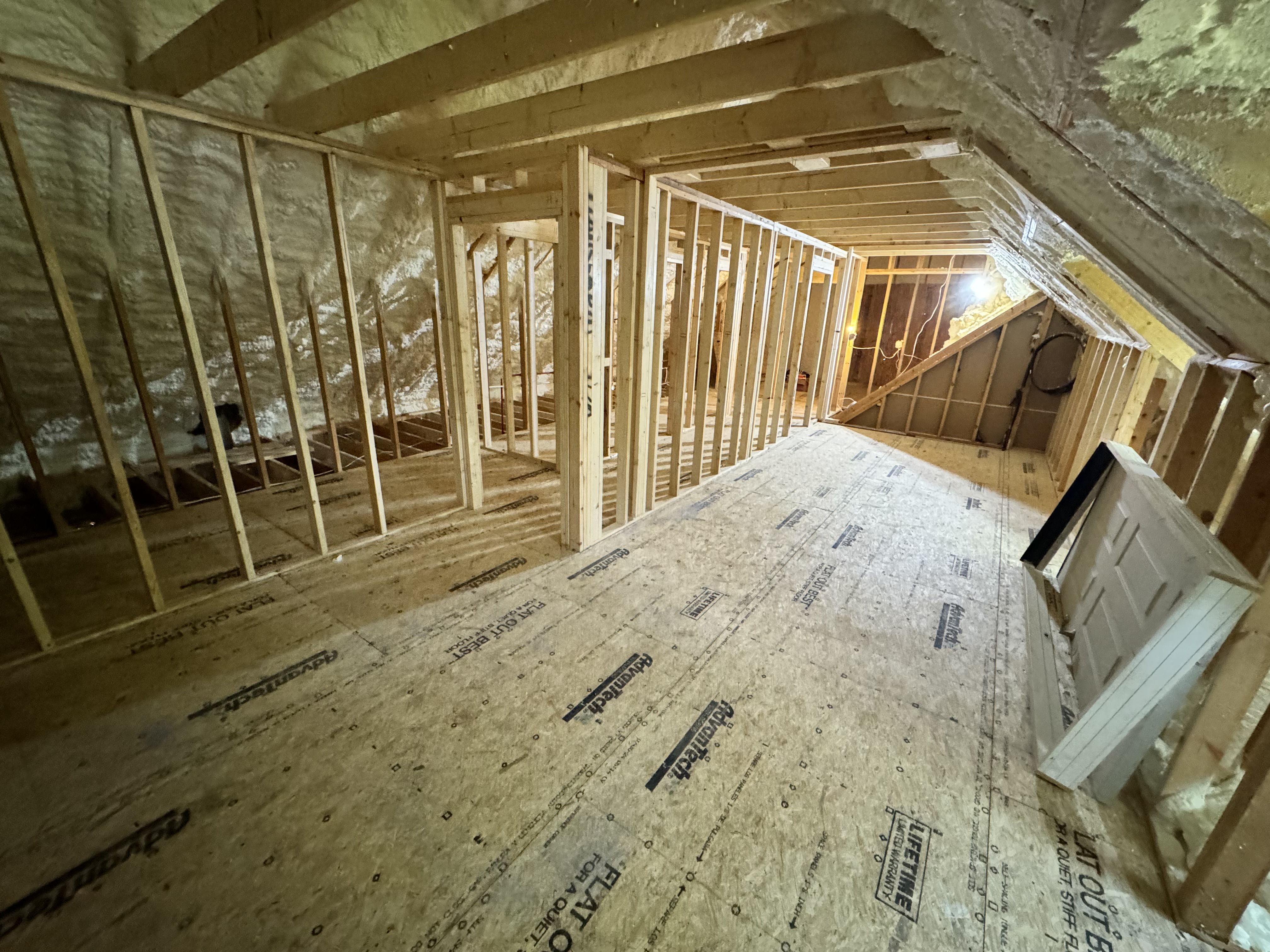 Rooms defined with spray foam insulation on roof deck and electrical rough-in