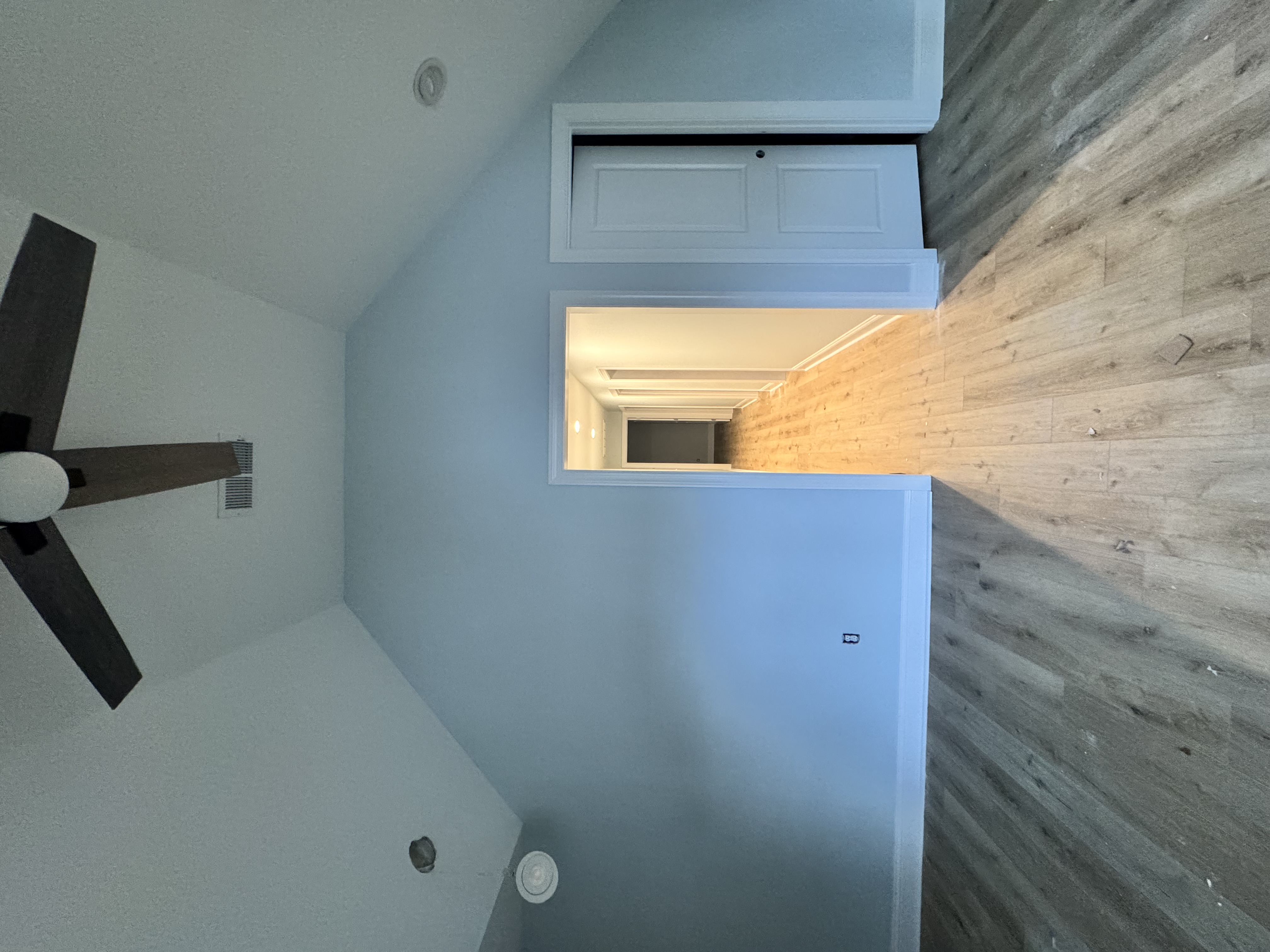 Finished attic bedroom with vaulted ceiling, gray vinyl plank flooring, and ceiling fan