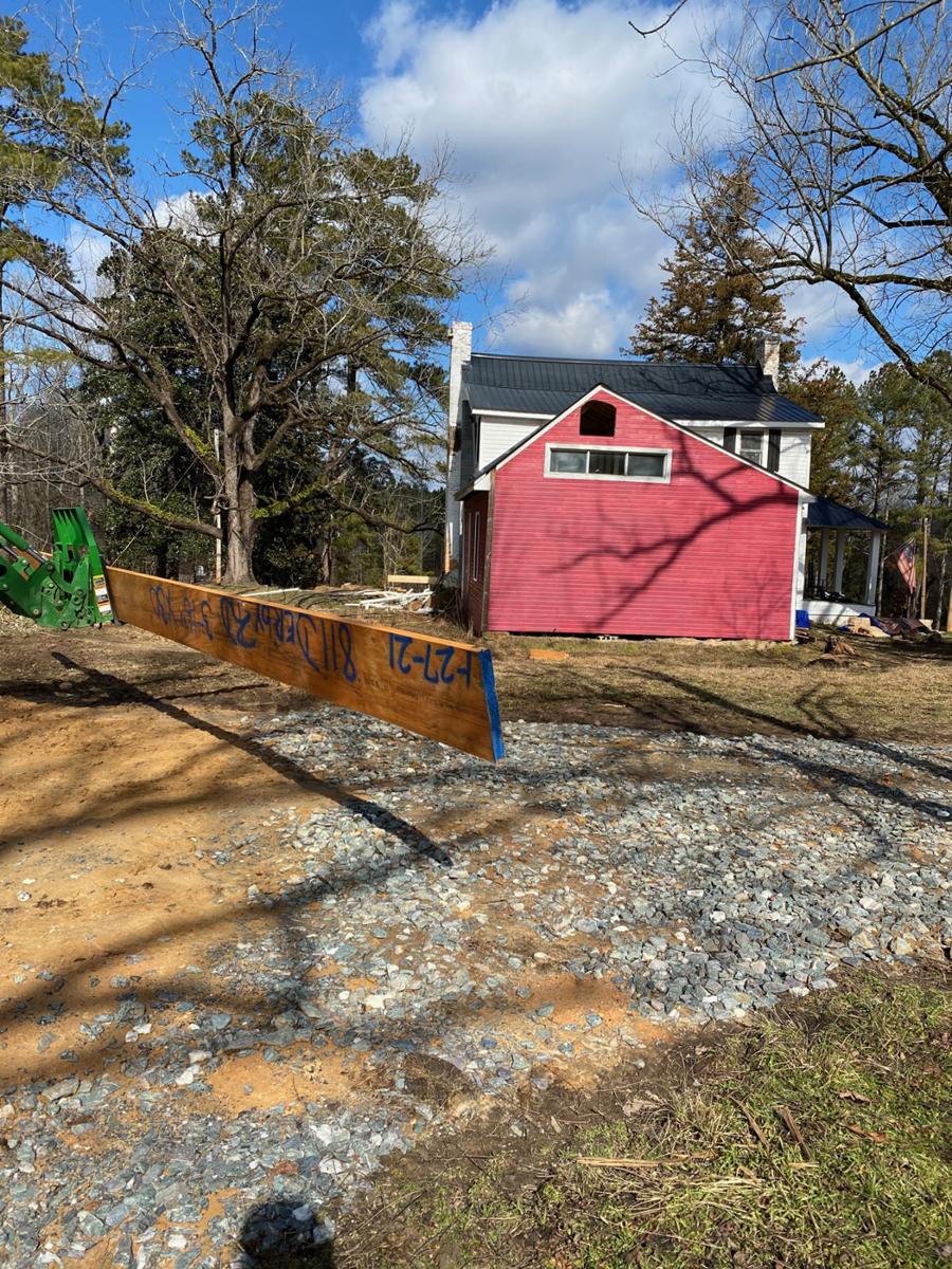 The new ridge beam staged in the yard with the main house behind it