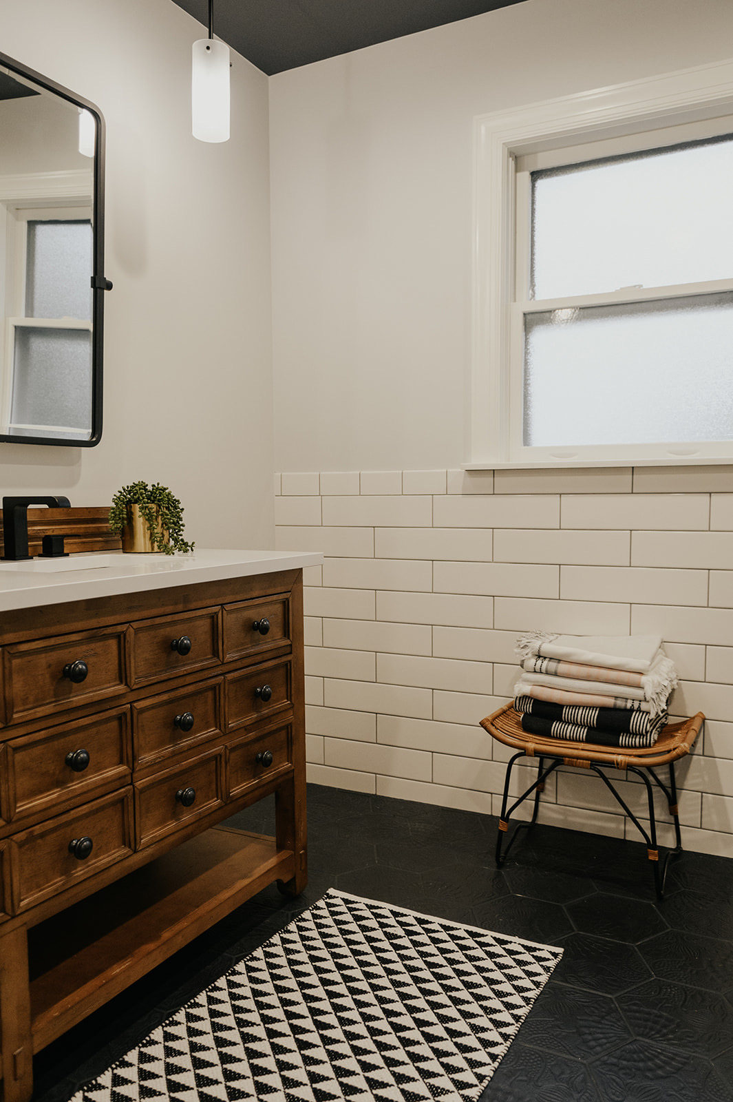 After: rustic wood double vanity with black-framed mirror and pendant lighting against subway tile