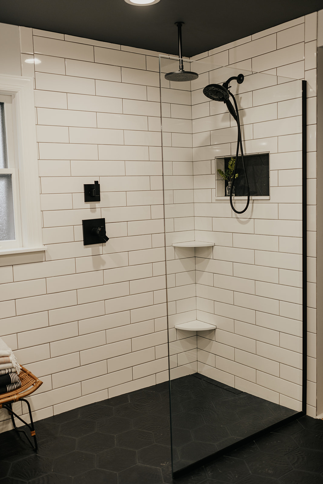 After: full view of the finished primary bath with vanity, walk-in shower, and dark hex floor