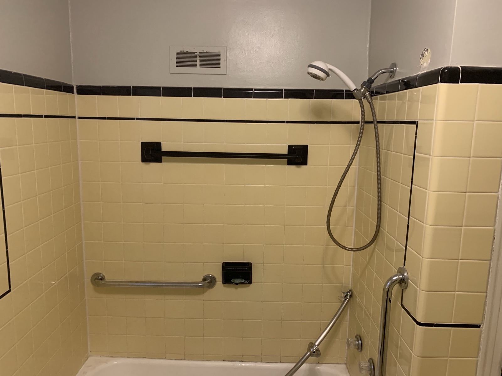 Before: original tub-shower combo with handheld and retrofit grab bars