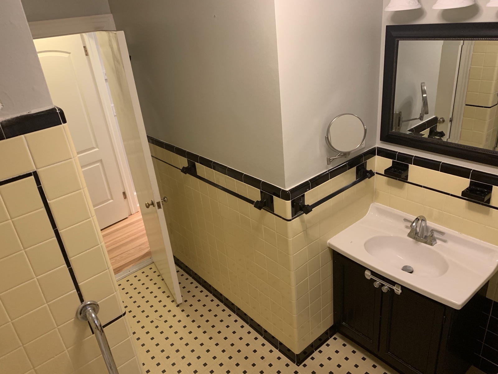 Before: dark single vanity, framed mirror, and yellow tile wainscot