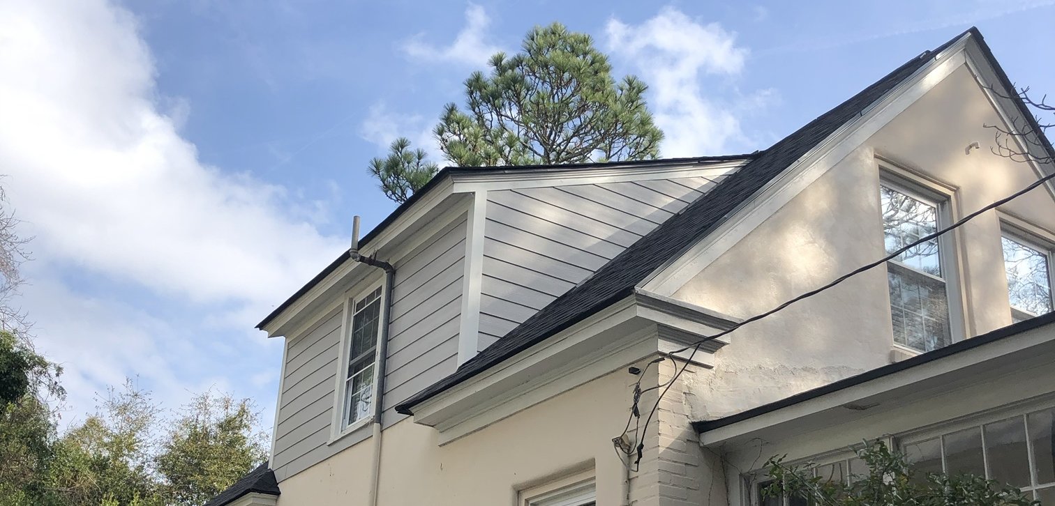 Finished stucco house in Southern Pines with the dormer re-sided in gray James Hardie lap siding with white trim under a new dark architectural shingle roof