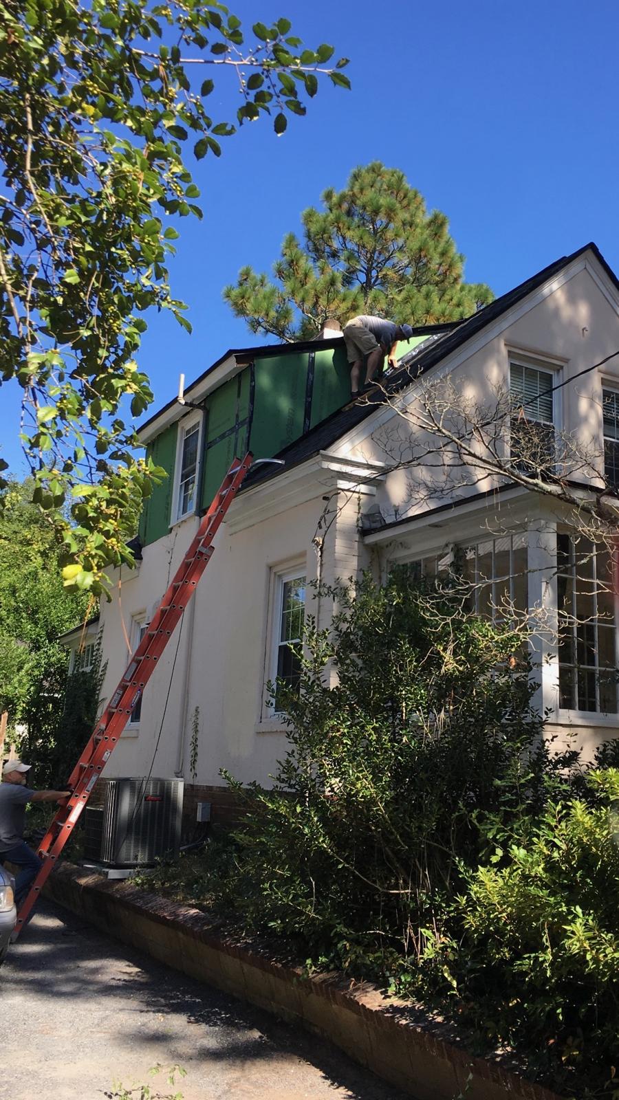 Stucco house in Southern Pines with a ladder to the roof and the dormer sheathed in green ZIP System panels during the roof replacement